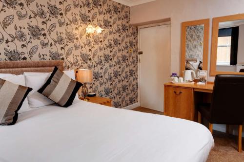 a bedroom with a bed and a desk with a computer at Best Western The George Hotel, Swaffham in Swaffham