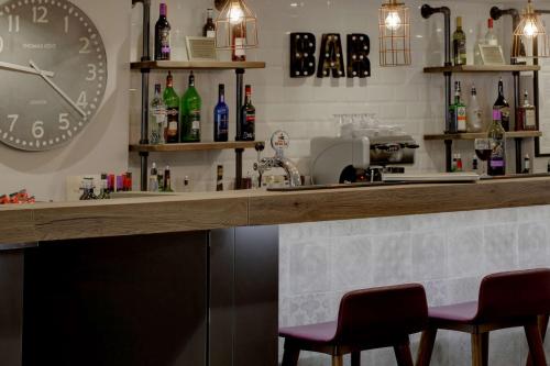 a bar with two chairs and a clock on the wall at Best Western White House Hotel in Watford