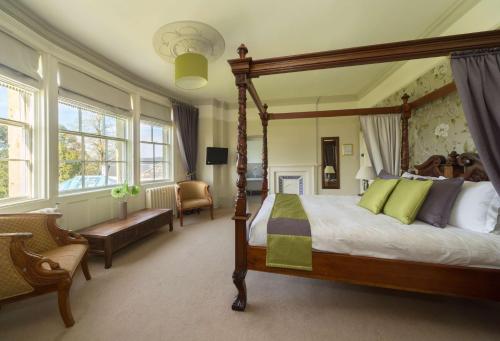 a bedroom with a canopy bed and a chair at Leigh Park Country House Hotel & Vineyard, BW Signature Collection in Bradford on Avon