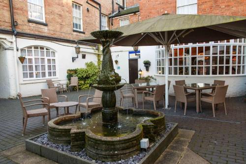 a fountain in the middle of a courtyard with tables and chairs at Best Western Lichfield City Centre The George Hotel in Lichfield