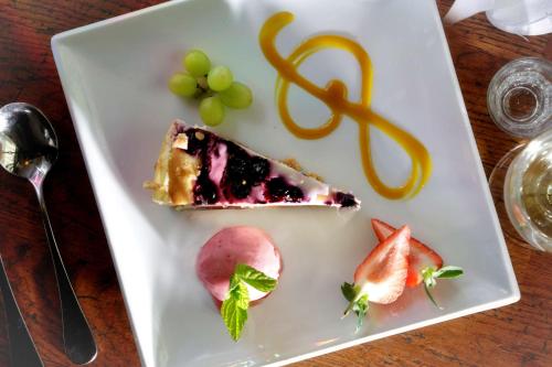 a white plate with a piece of cake and fruit at Normanton Park Hotel, Sure Hotel Collection by Best Western in Oakham