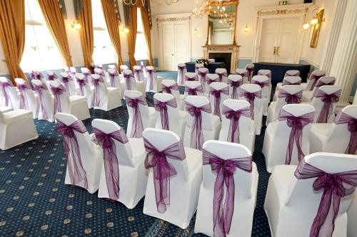 a row of white chairs with bows in a room at Best Western Lichfield City Centre The George Hotel in Lichfield