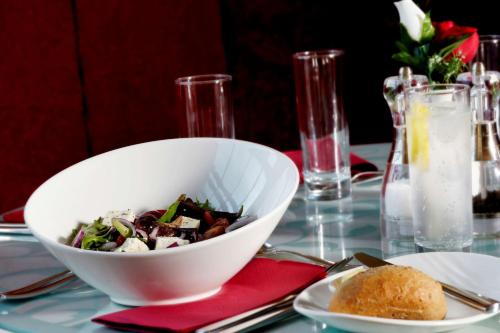 a bowl of salad on a table with a plate of food at Best Western Plus Pastures Hotel in Doncaster