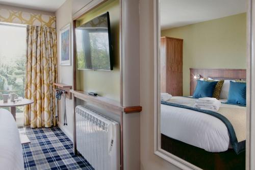 a hotel room with a bed and a mirror at Best Western Plus Pinewood Manchester Airport-Wilmslow Hotel in Handforth