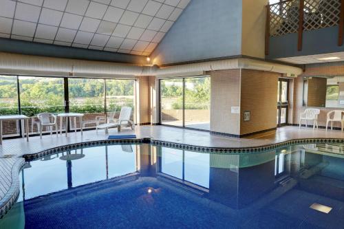 a large swimming pool with tables and chairs in a building at Passage House Hotel in Newton Abbot