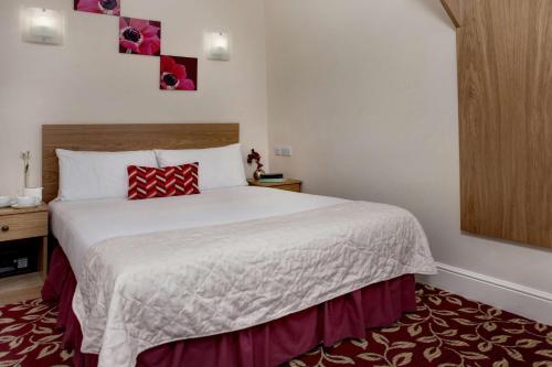 a bedroom with a large white bed with red pillows at Best Western Greater London in Ilford