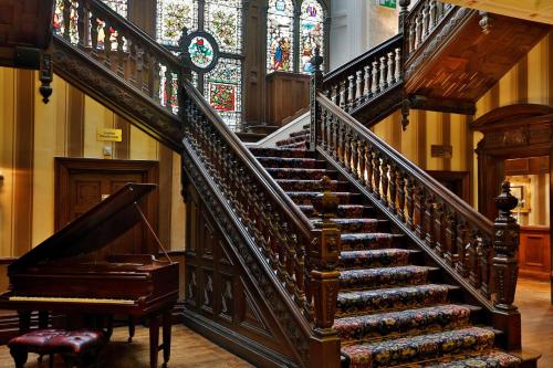 a staircase with a piano and a stained glass window at Oaks Hotel and Leisure Club in Burnley