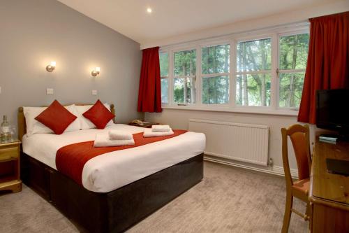 1 dormitorio con 1 cama grande y cortinas rojas en Best Western Andover, en Andover