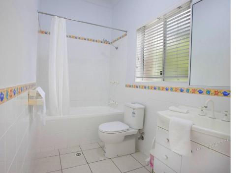 uma casa de banho branca com um WC, uma banheira e um lavatório. em Reef Suite em Agnes Water