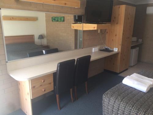 Zimmer mit einem Schreibtisch mit Stühlen und einem TV in der Unterkunft Alexander Motor Inn in Moree