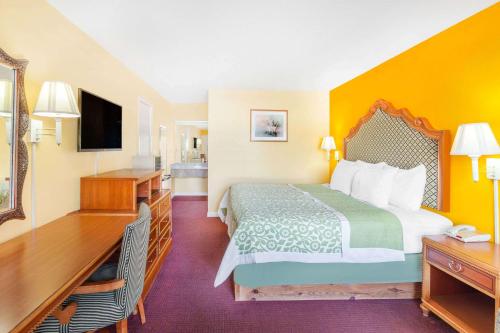a hotel room with a bed and a desk and a television at Days Inn by Wyndham Jacksonville in Jacksonville