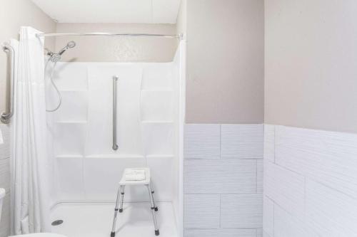 y baño con ducha blanca y taburete. en Super 8 by Wyndham Kingston en Kingston