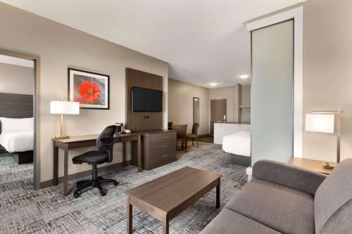 a hotel room with a couch and a desk and a bed at Days Inn & Suites by Wyndham Warman in Warman