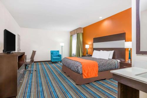 a hotel room with a bed and a flat screen tv at Days Inn & Suites by Wyndham Katy in Katy