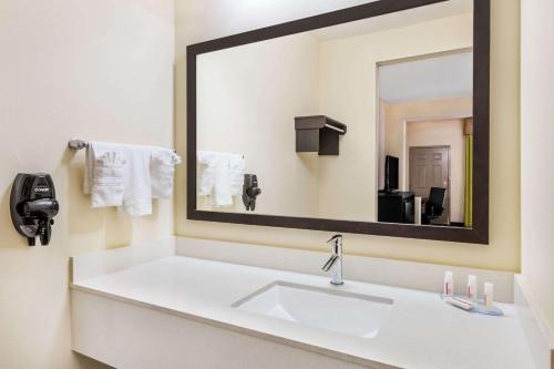 a bathroom with a sink and a large mirror at Days Inn & Suites by Wyndham Katy in Katy