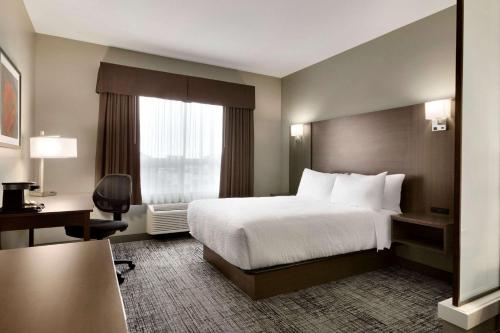 a hotel room with a bed and a window at Days Inn & Suites by Wyndham Warman in Warman