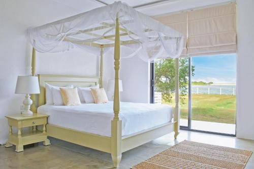 a bedroom with a canopy bed with a view of the ocean at Villa Santé in Kalpitiya