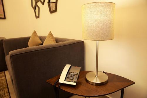 a lamp on a table next to a couch with a telephone at Downtown Hotel Apartments in Amman