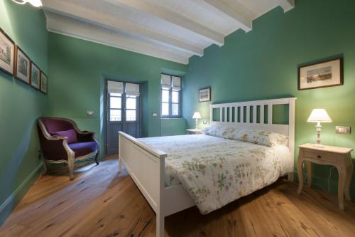 una camera da letto con pareti verdi, un letto bianco e una sedia di Isola Bella Apartments - Via Villa 9 a Stresa