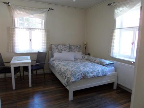 a bedroom with a bed and a table and two windows at Hof Berens in Hövelhof