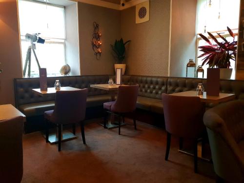 a restaurant with two tables and chairs and a bench at The Fairburn Hotel in Mauchline