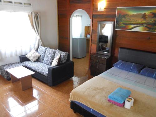 a living room with a bed and a couch at Rainbow Lodge in Pantai Cenang