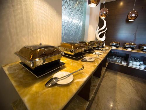 a buffet line with plates and utensils in a restaurant at ST Parklane Airport Hotel Chennai in Chennai