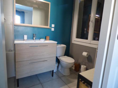 ein Badezimmer mit einem WC, einem Waschbecken und einem Spiegel in der Unterkunft Les Amandiers in Abeilhan