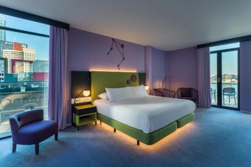 a bedroom with a large bed and a chair at Room Mate Bruno, Rotterdam in Rotterdam