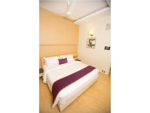 a bedroom with a large white bed with a purple pillow at ST Parklane Airport Hotel Chennai in Chennai