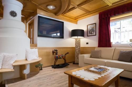 sala de estar con sofá y TV en la pared en Hotel Cirelle Suite & Spa, en Canazei