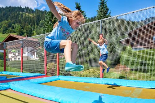 フラッハウにあるSonnberg Ferienanlageのトランポリンに飛び乗る少女