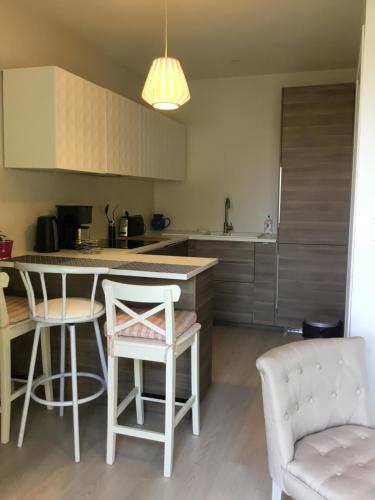 a kitchen with a counter and two chairs and a table at Chambres d'hôte Ô Bois Plage in Gujan-Mestras