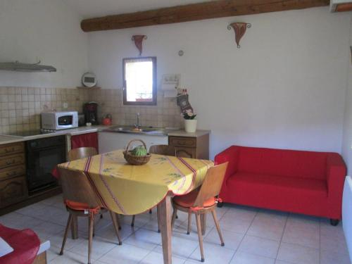 a kitchen with a table and a red couch at Gîtes des Cèdres in Crestet