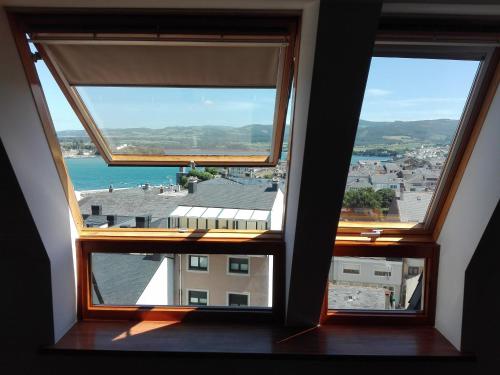リバデオにあるÁtico Ría del Eoの海の景色を望む客室内の窓3つ