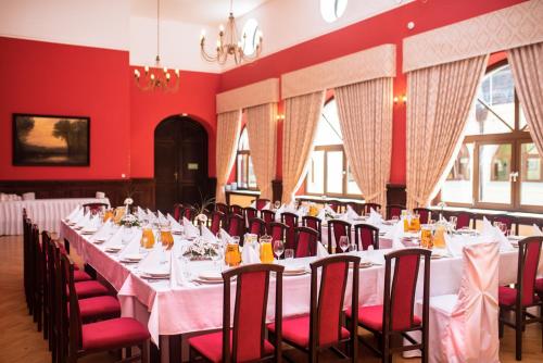uma sala de jantar com mesas brancas e paredes vermelhas em Pałac Krobielowice em Katy Wroclawskie