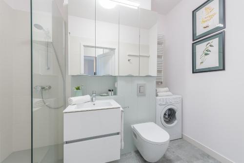 a white bathroom with a toilet sink and a washing machine at P&O Apartments Mokotów in Warsaw