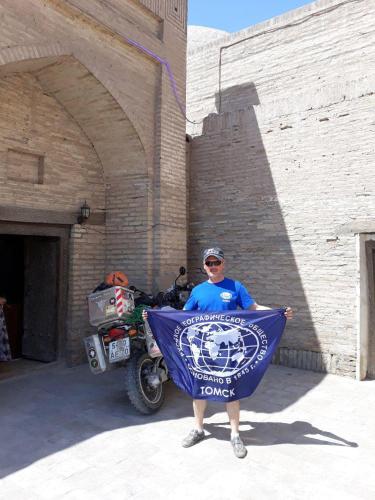 a man standing in front of a building holding a flag at Caravan Sarai Yotoqxona in Khiva