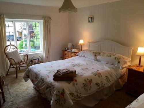 a bedroom with a bed with a white comforter and a window at Lower Ford Farm in Cullompton