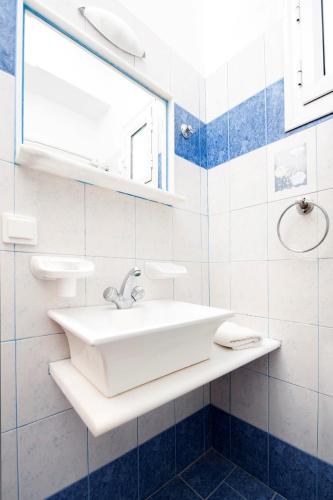 a white bathroom with a sink and a window at Dimitris Rooms in Manganari
