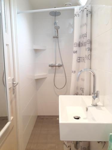 een witte badkamer met een wastafel en een douche bij Duinhuis26 in Egmond aan Zee