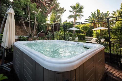 una bañera de hidromasaje en un patio trasero con sombrilla en Villa El Mirador, en Marbella