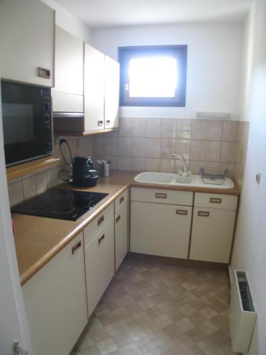 a small kitchen with white cabinets and a sink at Love nest munster in Munster