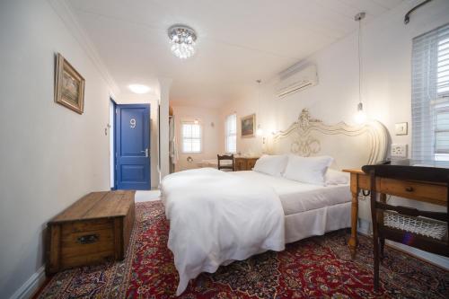 a bedroom with a large white bed and a blue door at Batavia Boutique Hotel in Stellenbosch