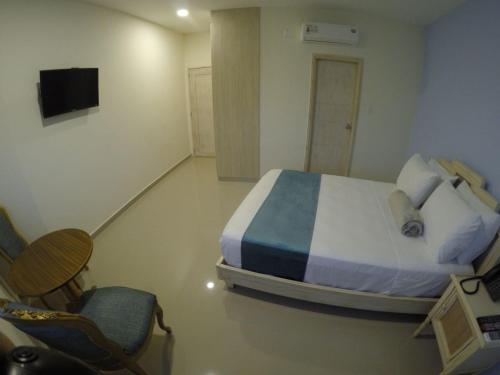 a bedroom with a bed and a chair and a television at Hotel Med Barranquilla Centro in Barranquilla