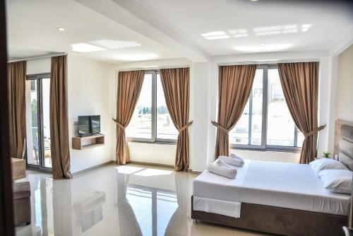 a bedroom with a bed and a tv and windows at Vista Apartments in Ulcinj