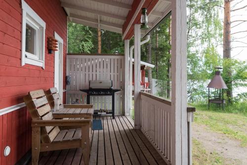 un porche de una casa roja con parrilla y bancos en Hiekkarannanlomat, en Kannonkoski