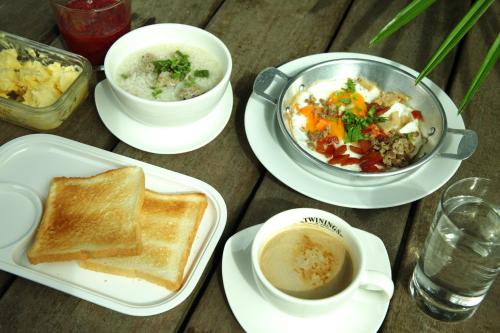 een tafel met borden vol eten, een kop koffie en toast bij Hatthatara Resort in Samut Songkhram