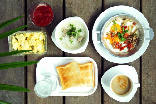 vier borden eten op een houten tafel bij Hatthatara Resort in Samut Songkhram