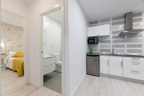 a kitchen with white cabinets and a bed in a room at La Pause in Arzúa